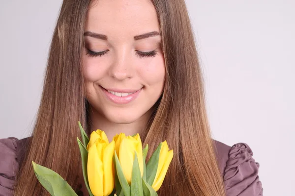 Schöne Frau mit gelben Tulpen — Stockfoto