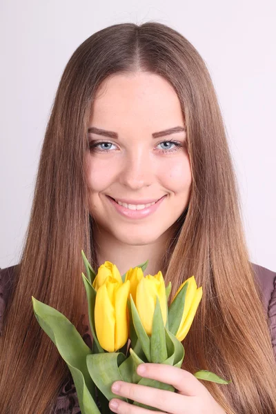 Mooie vrouw met gele tulpen — Stockfoto