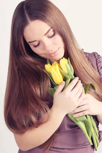 Vrouw met lang haar met gele tulpen — Stockfoto