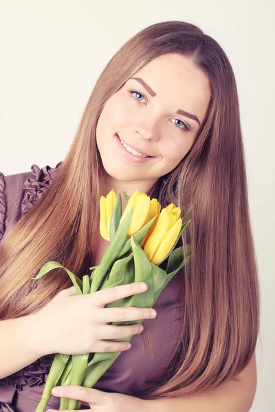 Žena s dlouhými vlasy s žluté tulipány — Stock fotografie