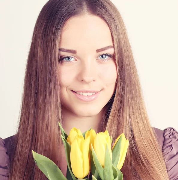 Krásná žena s dlouhými vlasy s žluté tulipány — Stock fotografie