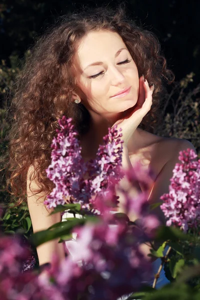 Vackra lockiga flicka med blommor — Stockfoto