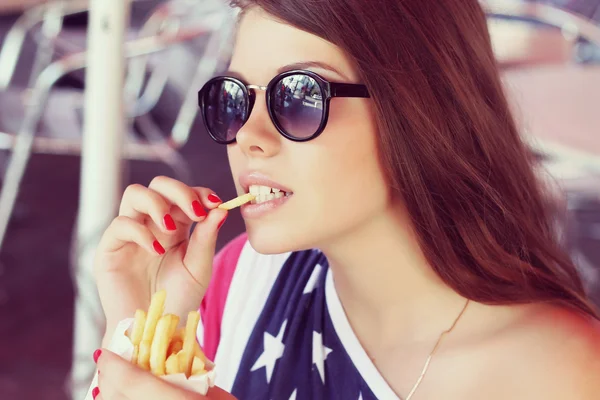 Amerikansk flicka äter pommes frites — Stockfoto