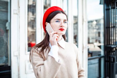 Şehirde kırmızı dudaklı ve güneş gözlüklü güzel bir genç kadın var.