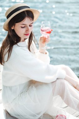 Gün batımında plajda yaz pikniği. Elinde bir bardak gül şarabı olan genç bir kadın. Hafta sonu pikniği.   