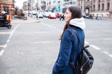 Sırt çantalı genç ve güzel bir kadın şehirde yürüyor.