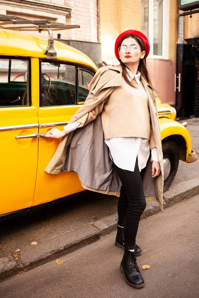 young beautiful woman in a yellow jacket and sunglasses standing on the street with a backpack