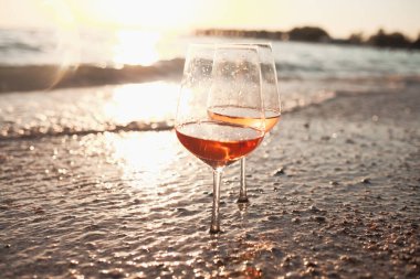 Gün batımında sahilde bir bardak şarap.