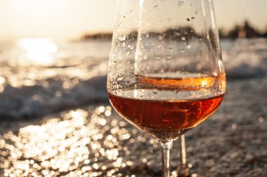 Gün batımında sahilde bir bardak şarap.