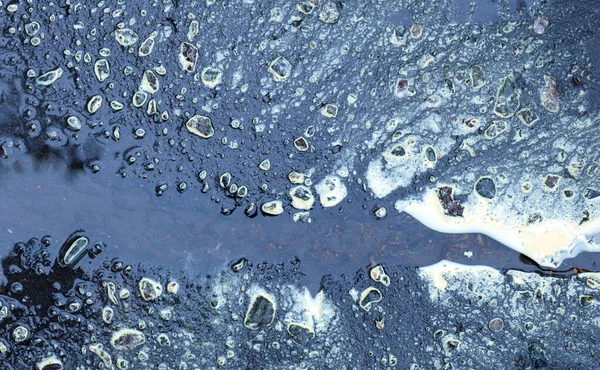 Asfalt yol birikintilerindeki soyut desenler.