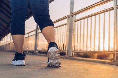 Kadın üst geçitte yürüyüş egzersizi yapıyor.