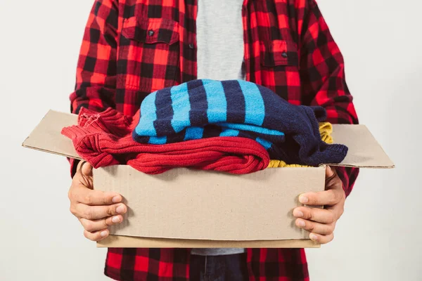 man holding a crate of second-hand clothes unused clothes