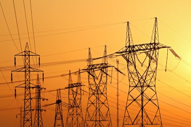 High voltage electrical pylons during sunset clipart