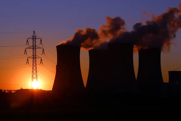 Башта високої напруги та димохід електростанції під час заходу сонця — стокове фото