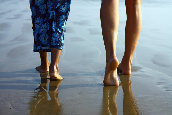 detail of child and girl legs walking on the beach