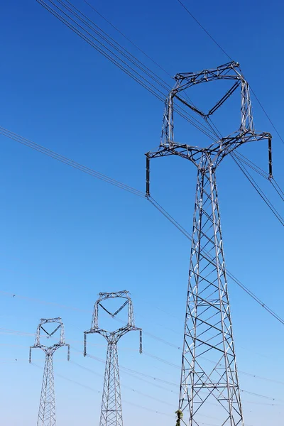 Drie hoogspanning pylonen onder de blauwe hemel — Stockfoto