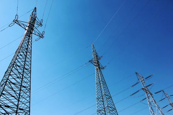 Grandes torres eléctricas de alto voltaje bajo el cielo azul — Foto de Stock