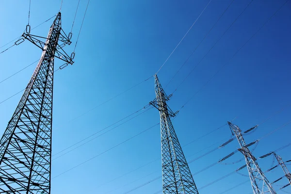 Stor högspänning elektriska torn under blå himmel Royaltyfria Stockfoton