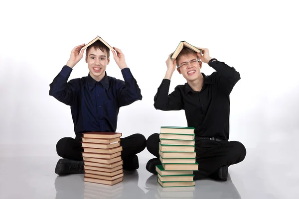 Dos adolescentes con libros en la cabeza — Foto de Stock