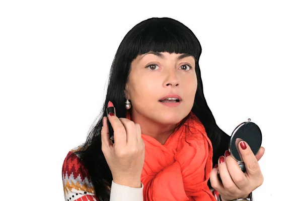Brunette vrouw schildert lippen voordat een spiegel — Stockfoto