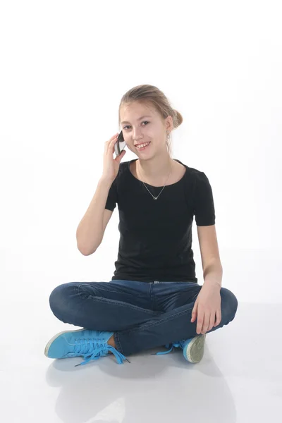 Teenage girl calling on the phone sitting on the floor — Stock Photo, Image