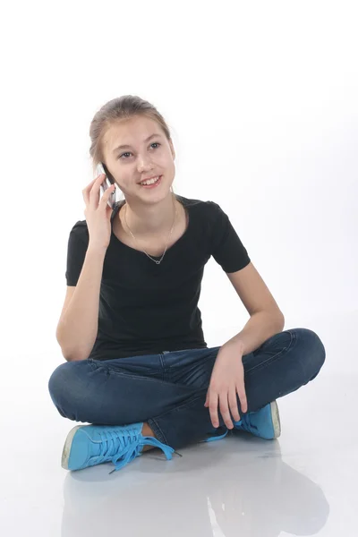 Tonårig flicka talar i telefon sitter på golvet — Stockfoto