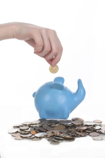 Ręka stawia monety w piggy bank na tle — Zdjęcie stockowe