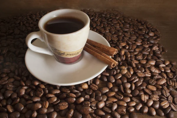 Kopp kaffe på en bakgrund kaffebönor och brunt trä vildsvin — Stockfoto