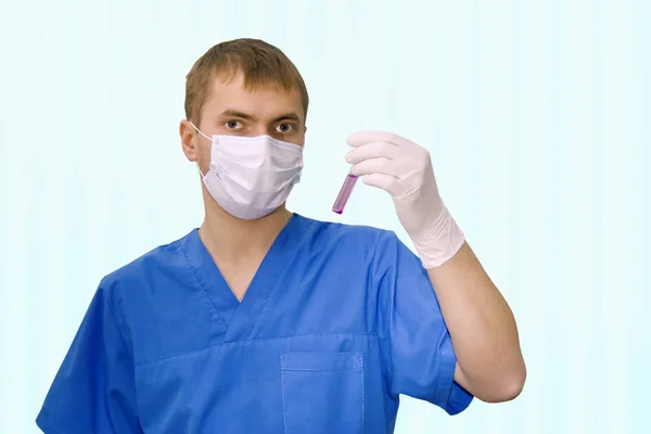 Doctor in a mask holding a test tube — Stock Photo, Image