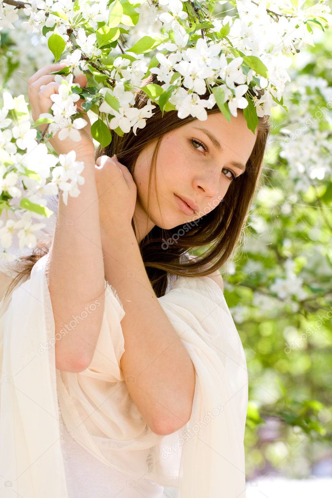 young beautiful girl in a white dress in blooming garden
