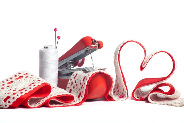 Mini machine sewing heart from red and white ribbons — Stock Photo, Image