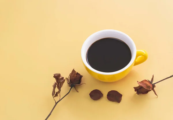 Gelbe Keramiktasse Mit Schwarzem Kaffee Neben Getrockneter Rose Auf Pastellfarbenem — Stockfoto