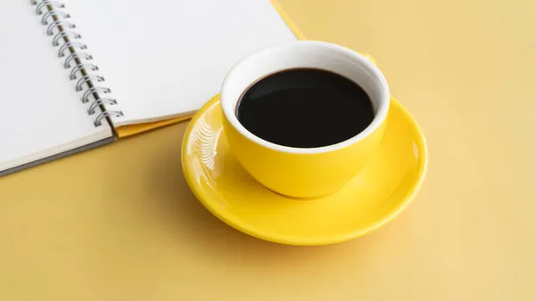 Gelbe Keramiktasse Mit Schwarzem Kaffee Vor Verschwommenem Aufgeschlagenem Buch Auf — Stockfoto