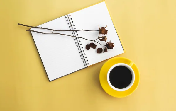 黒コーヒーと黄色のセラミックカップが開いて本と乾燥バラの横に置かれ 背景に — ストック写真