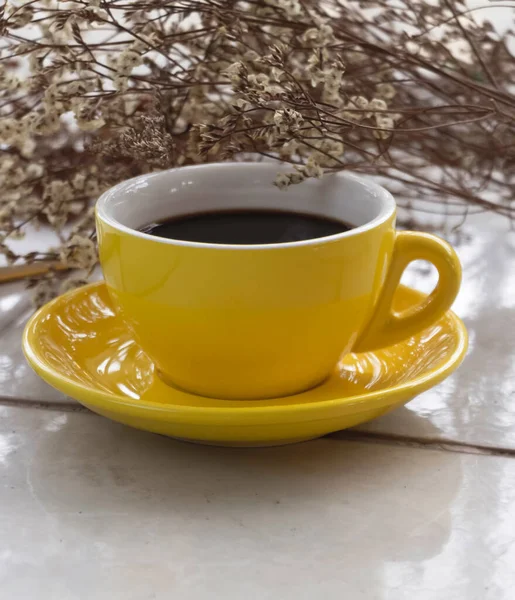 Gelbe Keramiktasse Mit Schwarzem Kaffee Neben Getrockneter Blume Verschwommenes Licht — Stockfoto