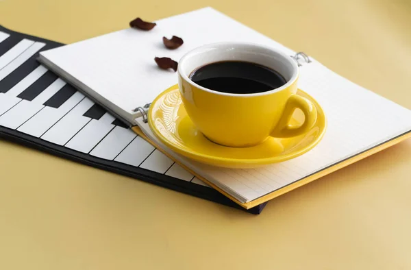 Gelbe Keramiktasse Mit Schwarzem Kaffee Auf Geöffnetem Buch Und Klaviertasten — Stockfoto