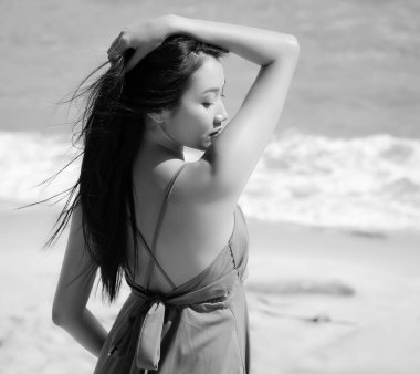 Güzel bir kadın elini kaldırır, kafasına dokunur ve gözlerini kapatır, modelin portresi, siyah ve beyaz tonu, bulanık ışık.