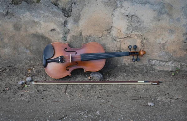 小提琴和弓放在磨擦的地面地板 旧墙壁 音响器材 模糊的灯光周围 — 图库照片