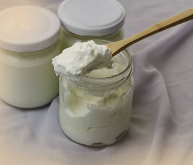 Tahta kaşıkta yoğurdun seçici odak noktasında açık şişeyi aç, bulanık ışığı etrafında tut.