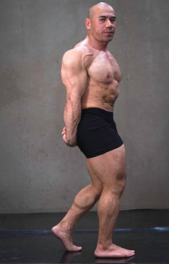 Formda ve sağlam vücutlu genç bir adam. Güçlü kasları ve vücut geliştiricisi pozu veriyor.