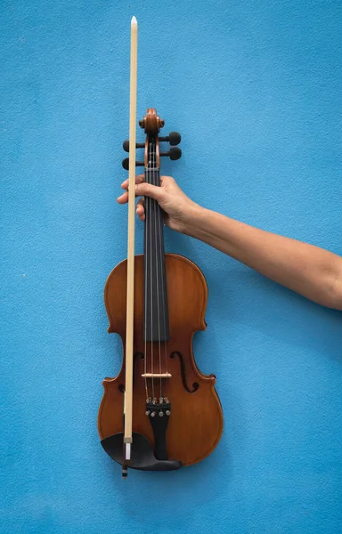 Violin and bow was holding by human hand,show part of acoustic instrument