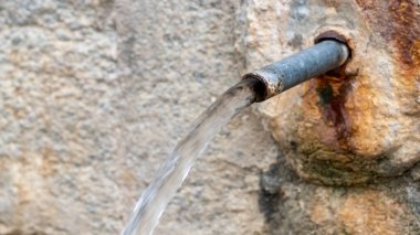 Antik bir doğal taştan akan kaynak suyu.