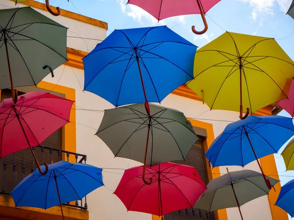 Színes esernyők lógnak a kék ég fölött. — Stock Fotó
