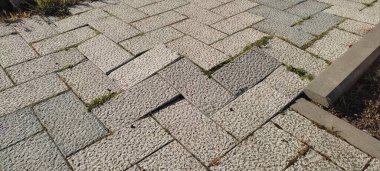 Bir kaldırım fotoğrafı, düz olmayan bir yolda kırmızı renkli yapay bir taş..