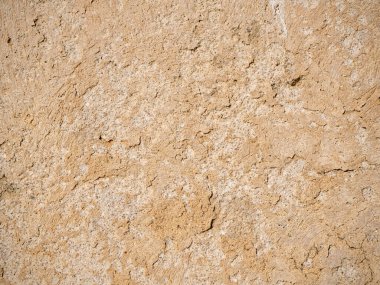 Zamanla yıpranmış sarı bir kum duvarının dokusu