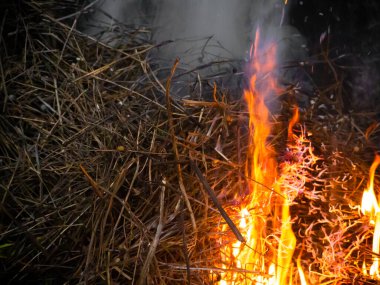 Kışın kırsal bir bölgede yanan bir jüt sopasıyla saman kazığı yakılıyor.
