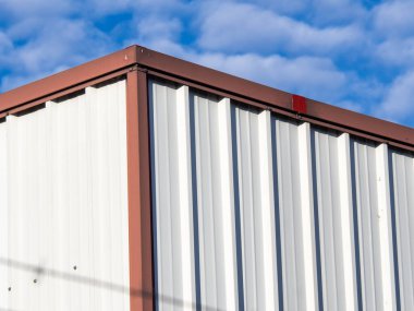 Mavi gökyüzünün altındaki çelik beyaz ve kırmızı bir depoda. HD resim