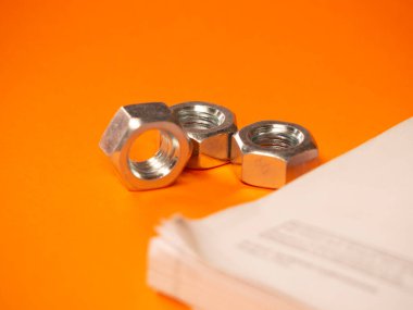 chrome-plated metal nuts on orange background. Technology concept. HD image