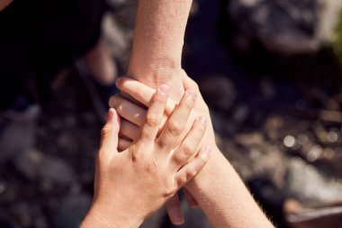 Üç kollu Latin bir aile. Anne ve ikizler. Birlik, destek, koruma ve mutluluk kavramı. Odaklanamayan koyu arkaplan. Nehir taşları arka plan.