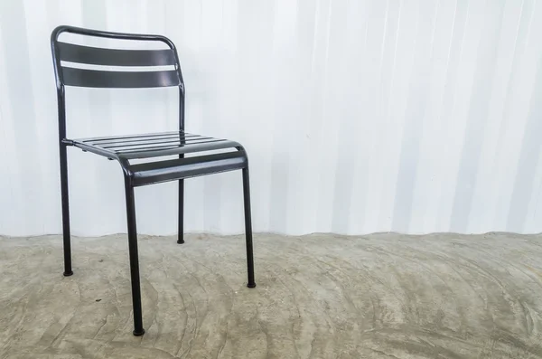 Black metal chair on gray wall — Stock Photo, Image